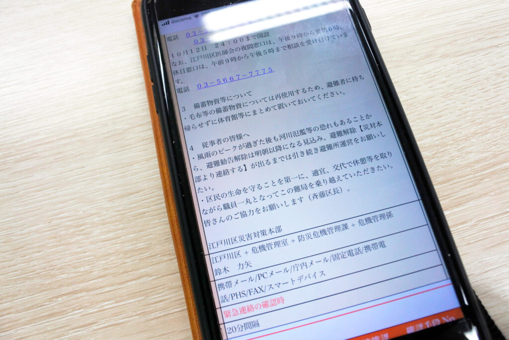 区長から避難所職員への激励メッセージが届いたスマートフォン画面。連絡・伝達だけでなく心の通った使い方の事例として、備蓄物資の取扱いや避難勧告解除までの運営継続の案内、江戸川区災害対策本部の連絡先が表示されている